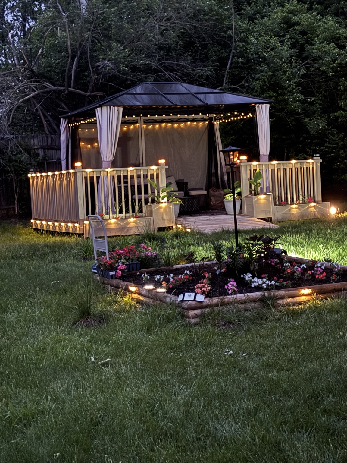 Wendell’s outdoor movie room glowing with lights beside the garden